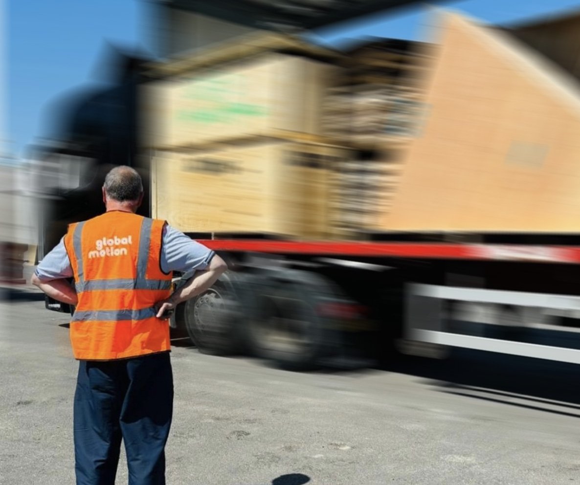 A man in an orange high vis looking at a truck loaded with boxes